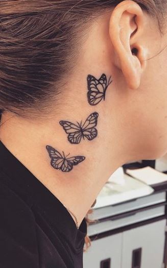 Woman receiving butterfly tattoo at her neck stock photo