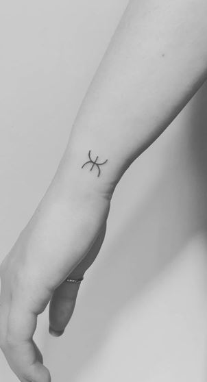 Fine line pisces zodiac symbol tattoo done behind the