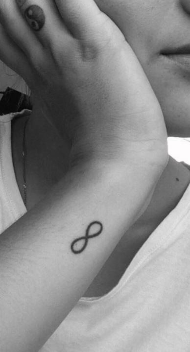 Tiny infinity symbol tattooed on the upper arm