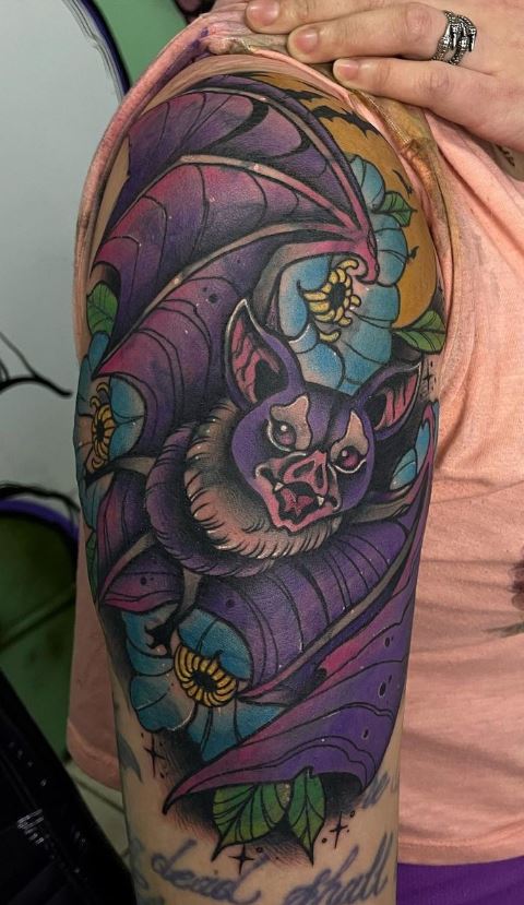 Colorful bat tattoo located on the upper arm,